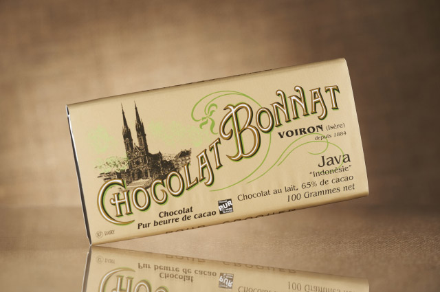 L’image du centre présente une tablette de chocolat Bonnat 65% de cacao Grand cru Lait Java, dans son emballage beige clair, sur fond beige foncé.